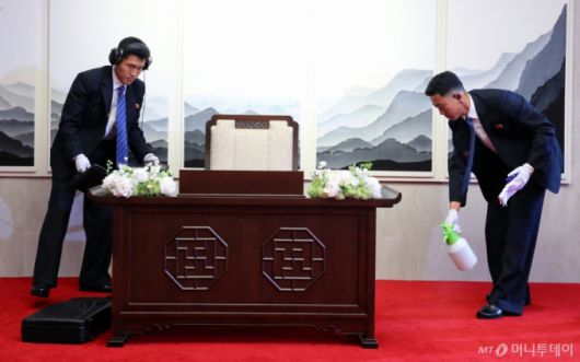 27일 오전 판문점 평화의 집에 마련된 김정은 국무위원장이 방명록을 작성할 책상과 의자에 북측 경호원들이 분무기를 활용해 소독약을 뿌리고 닦아내고 있다. 또 다른 경호원은 도청장치 검색을 하고 있다. /사진=한국공동사진기자단