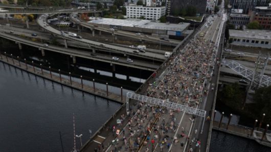 12일(현지시간) 미 오리건주 포틀랜드 번사이드 브리지에서 '나체 자전거 시위'(Naked Bike Ride) 참가자들이 도널드 트럼프 대통령의 주 방위군 투입 시도에 항의하며 도로에 누워 시위하고 있다. /AP=뉴시스