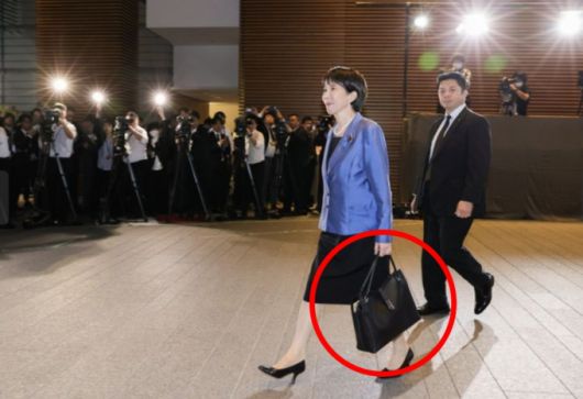 다카이치 사나에 일본 총리가 지난 21일 도쿄 총리 관저에 들어서고 있다. 화제가 된 붉은원 안의 하마노 가죽공예 가방. /사진=일본 총리관저 홈페이지 캡처)