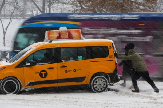 대형 겨울폭풍이 미국 전역으로 확산되는 가운데 25일(현지시간) 뉴욕 센트럴파크 인근에서 시민들이 눈길에 멈춘 택시를 밀어주고 있다. /로이터=뉴스1