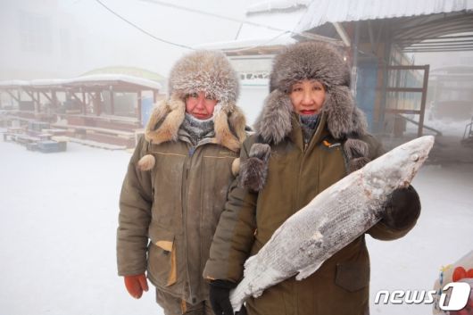 15일(현지시간) 러시아 야쿠츠크에서 생선을 파는 상인 마리나 크리볼루츠카야와 마리안나 우가이가 딱딱하게 언 생선을 든 채 사진을 찍고 있다. 이들 가게엔 냉동 창고가 따로 없다. /사진=뉴스1