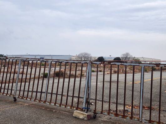 옛 한국GM 군산공장의 출고 대기장. 굳게 닫힌 녹슨 철문 뒤로 잡초가 무성한 빈 땅과 멀리 빛바랜 쉐보레 로고가 보인다. GM은 지난 2018년 군산공장 가동을 중단했고 이듬해 매각했다. /진상훈 기자