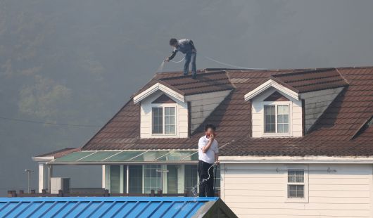 28일 오후 2시 1분쯤 대구 북구 노곡동 함지산에서 산불이 발생한 가운데 주민들이 주택 지붕에 물을 뿌리고 있다. /연합뉴스