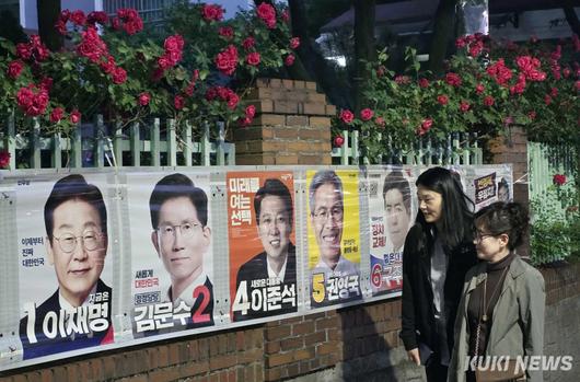 25일 대전광역시 서구 둔산동의 한 아파트 담장에 만개한 장미꽃 아래 유권자들이 제21대 대통령 선거 벽보를 살펴보고 있다.