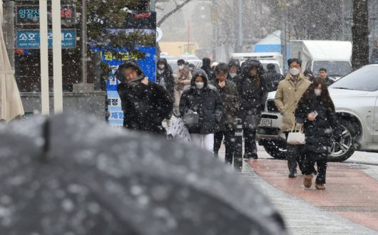 12일 서울 여의도 거리에서 시민들이 점심시간 내리는 눈을 맞으며 걷고 있다.