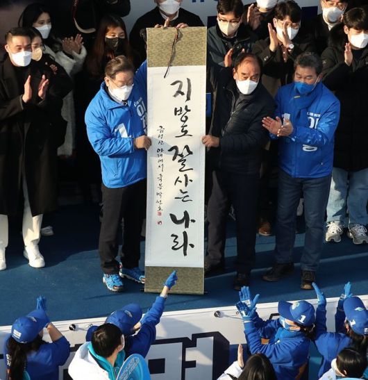 지난 2월18일, 이재명 당시 더불어민주당 대선후보가 전남 나주시 금성관 정수루에서 ‘지방도 잘 사는 나라’라는 휘호가 담긴 족자를 선물받고 있다. ⓒ뉴시스