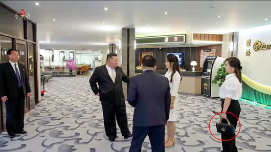 김정은 북한 국무위원장의 아내 리설주 여사가 이탈리아 명품 브랜드 '구찌'(붉은 원)로 추정되는 검은색 핸드백을 멘 모습이 포착됐다. [사진=조선중앙TV화면]