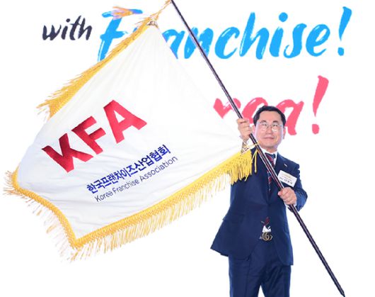 나명석 신임 한국프랜차이즈산업협회장(웰빙푸드 회장)이 19일 오후 서울 여의도 콘래드 서울 그랜드볼룸에서 열린 한국프랜차이즈산업협회 협회장 이·취임식 및 비전 선포식에서 협회기를 흔들고 있다. [사진=정소희 기자]