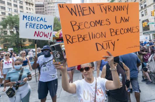 미국의 코로나19 백신 부스터샷 접종 일정이 늦춰질 것으로 예상되는 가운데 지난달 25일(현지시간) 뉴욕에서 백신접종 의무화에 반대하는 이들이 시위를 하고 있다. 한 여성이 백신접종 의무화를 독재라고 규정하고 "독재가 법이 되면 반란은 의무가 된다"는 문구가 새겨진 팻말을 들고 있다. AP뉴시스