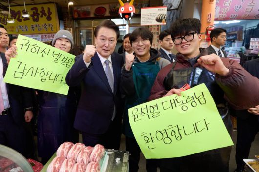 윤석열 대통령이 설 명절을 앞두고 지난 8일 서울 광진구 중곡제일시장을 찾아 환영 문구가 쓰인 팻말을 든 상인들과 기념촬영을 하고 있다. 대통령실 제공