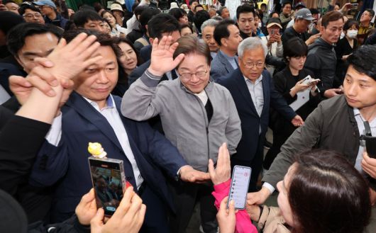 민심을 청취하는 '경청 투어'에 나선 이재명 더불어민주당 대선후보가 3일 강원도 양양군 양양시장에서 상인 및 주민들에게 인사를 하는 가운데 이 후보 경호원들 대인 직접 접촉을 차단하고 있다. /사진=뉴시스