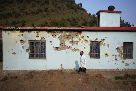 지난 7일 수요일, 인도 라조우리(Rajouri)에서 한 남성이 파키스탄의 포격으로 손상된 건물 옆을 지나가고 있다. 뉴시스 외신화상