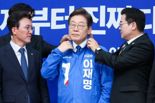 박찬대 더불어민주당 대표 직무대행 겸 원내대표가 지난 4월 서울 여의도 국회에서 열린 최고위원회의에서 이재명 대선 후보에게 선거복을 입혀준 뒤 옷깃을 정리하고 있다. 선거복 기호1번의 적색 삼각형이 눈길을 끈다. /사진=뉴스1