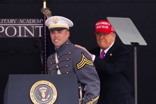 도널드 트럼프 대통령이 24일(현지시간) 미국 뉴욕 웨스트포인트에서 열린 미 육군사관학교 졸업식에서 육군 블랙나이츠의 미식축구 쿼터백인 졸업생 브라이슨 데일리의 등을 두드리며 격려하고 있다. AP 뉴시스
