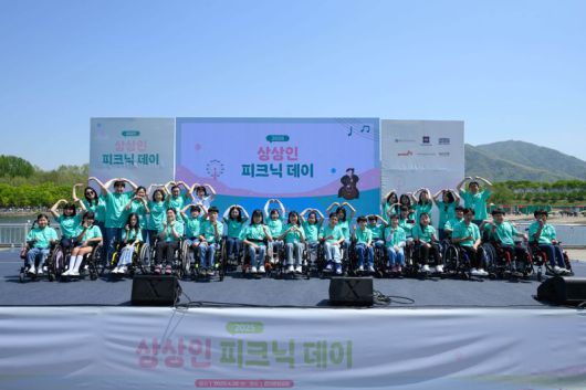 상상인그룹이 지난 4월 26일 경기도 하남 미사경정공원에서 개최한 ‘2025 상상인 피크닉데이’에서 ‘상상휠하모니 오케스트라’ 단원들과 기념촬영을 하고 있다. 상상인그룹 제공