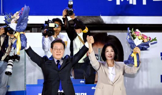 이재명 당선자와 부인 김혜경 여사가 4일 오전 당선이 확실시되자 서울 여의도 국회 앞을 찾아 꽃다발을 받아 들어 보이고 있다. 뉴스1