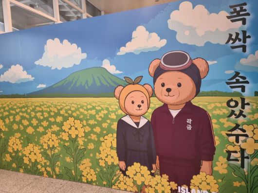 제주공항 1층에서 제주 감성 의류브랜드 '아일랜드 프로젝트'가 드라마 '폭싹 속았수다'를 모티브로 한 배경 그림을 걸어두고 있다. 사진=김동호 기자