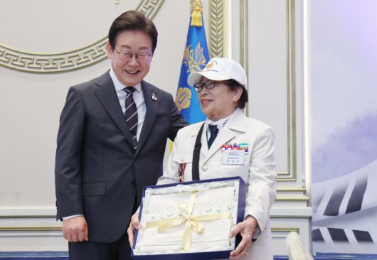 이재명 대통령이 27일 청와대 영빈관에서 열린 '호국보훈의 달, 대통령의 초대' 행사에서 특별초청 대상자인 6·25전쟁 참전유공자 이춘자 참전용사에게 광목이불 선물을 전달 후 미소짓고 있다. 대통령실통신사진기자단
