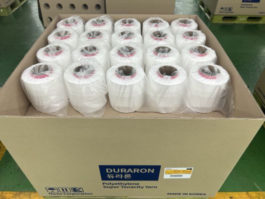 생산공정을 거쳐 출고 대기 중인 '듀라론-쿨' 냉감 원사. 휴비스제공                                    '듀라론-쿨' 원사로 제작된 냉감침구 제품과 신규 정품택 3종. 휴비스제공