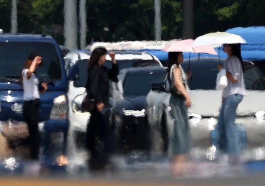 25일 오후 지열로 인한 아지랑이가 피어오르는 서울 시내를 시민들이 걸어가고 있다. 뉴시스