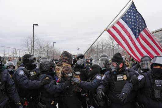 지난 15일(현지시간) 미 미네소타주 미니애폴리스 헨리 위플 연방청사 건물 앞에서 미국 국기를 흔들며 시위하던 남성이 경찰에 체포되고 있다. 사진=뉴시스