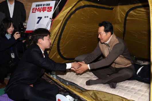 장동혁 국민의힘 대표가 21일 오전 서울 여의도 국회 로텐더홀에서 '민주당의 공천 뇌물·통일교 게이트 특검 수용'을 촉구하며 단식농성 중 이준석 개혁신당 대표와 대화를 하며 손을 잡고 있다. 뉴시스