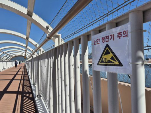 부산의 보행교 '감동나룻길 리버워크'에 난간 정전기 발생을 주의하는 안내문이 걸려 있는 모습. 뉴시스