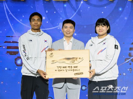 유승민 대한체육회장이 선수단의 액운을 막고 행운을 기원하는 마음을 담은 '액막이 명태' 기념품을 선수대표 나마디 조엘 진(육상), 김하윤(유도) 에게 전달하고 있다.  사진제공=대한체육회