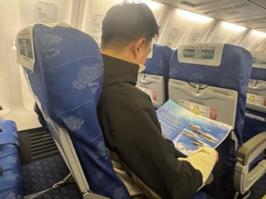 한·중 이중언어 잡지 <진챠오>의 특집 지면을 읽고 있는 승객 [사진=산둥항공]