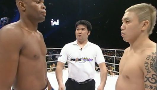 초난 료(오른쪽)가 2004년 일본 Pride 연말 대회 경기 시작 전 안데르송 시우바와 마주 보고 있다. 훗날 제5대 UFC 미들급 챔피언이 되는 시우바는 3라운드 3분 8초 만에 초난의 뛰어 날아 가위차기 및 다리 묶어 돌려 꺾기 연계 기술에 항복했다. 사진=TKO