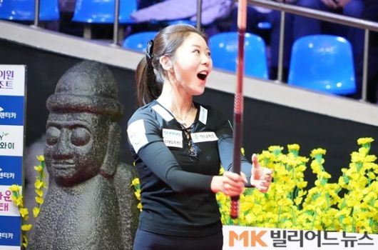 우승을 확정짓는 마지막 뒤돌리기를 성공한 뒤 큐를 들어올리며 세레머니하고 있는 김가영.