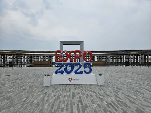 워터플라자 앞에 서 있는 엑스포2025 조형물. 뒤로 분수쇼가 펼쳐지는 오브제와 그랜드링의 모습이 보인다. [도쿄 = 이승훈 특파원]