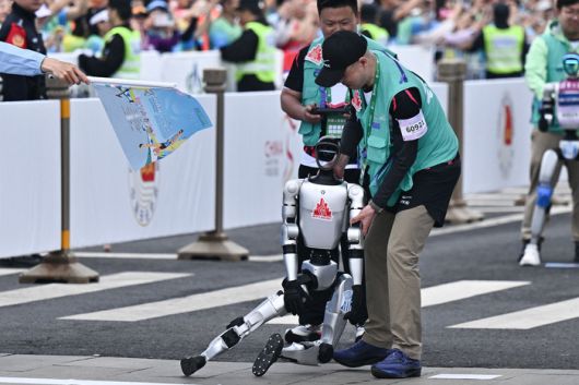19일 중국 베이징 휴머노이드 하프 마라톤 대회에 참가한 한 로봇이 출발지점에서 제어가 안돼 쓰러지고 있다. [AFP = 연합뉴스]