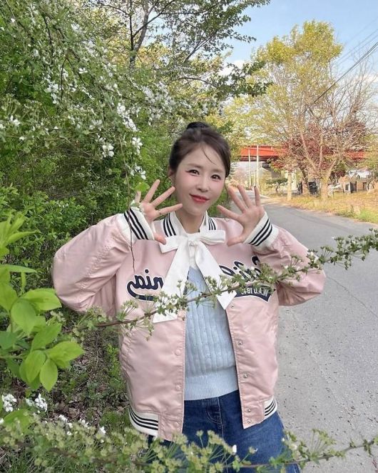 신지는 파스텔 핑크 컬러의 바시티 점퍼에 큼직한 화이트 리본 블라우스를 매치해 순식간에 ‘교복 코어’ 감성을 소환했다. 사진=신지 SNS