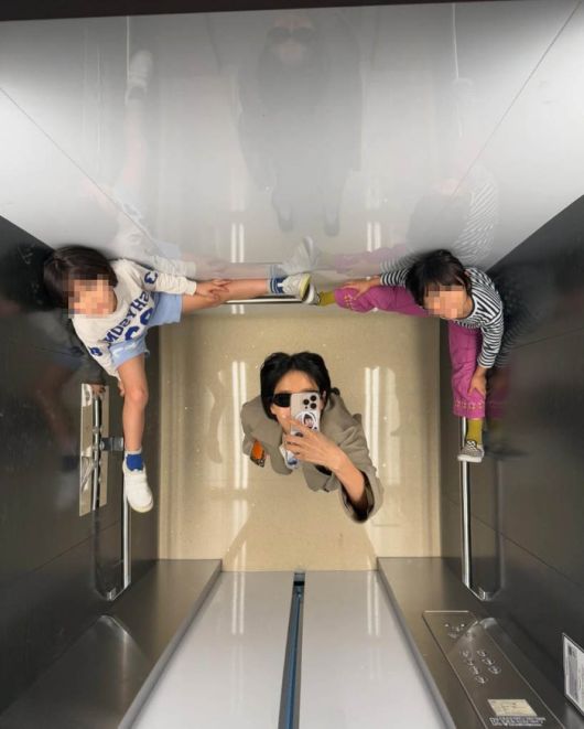 엘리베이터 거울 셀카 사진 속 아이들이 신발을 신은 채 손잡이에 올라탄 모습이 논란을 불러일으켰다.사진=김나영 SNS