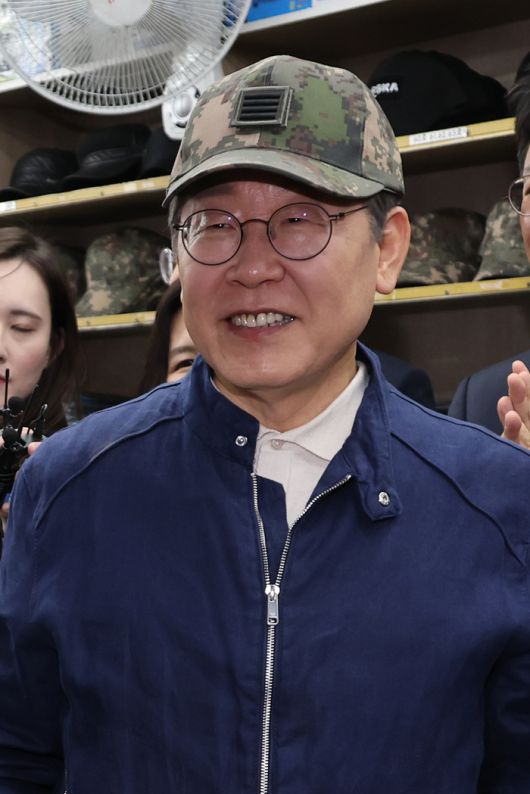 더불어민주당 이재명 대선 후보가 ‘골목골목 경청투어’ 접경지역 방문 이틀째인 2일 강원도 화천군 중앙로의 한 군장점에서 김병주 최고위원이 사준 병장 계급장이 달린 육군 모자를 쓰고서 상인과 대화하고 있다. [사진=연합뉴스]