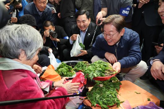더불어민주당 이재명 대선 후보가 ‘골목골목 경청투어’ 접경지역 방문 이틀째인 2일 강원도 인제군 원통전통시장에서 엄나무순을 사며 어르신과 대화하고 있다. [사진=연합뉴스]