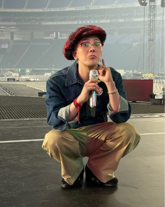 동그랗게 웅크린 채 마이크를 든 지드래곤이 장난기 가득한 표정을 짓고 있다.사진=지드래곤 SNS