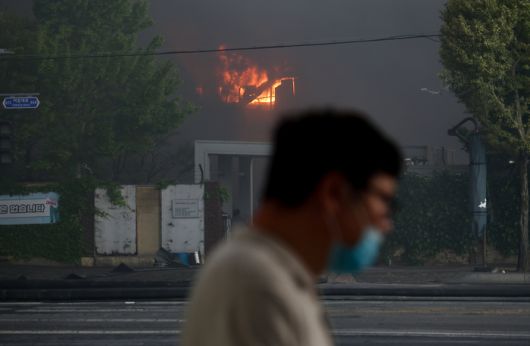 17일 오후 광주 광산구 송정동 금호타이어 광주공장에서 화재로 연기가 나오는 가운데 한 시민이 마스크를 끼고 이동하고 있다. 연합뉴스