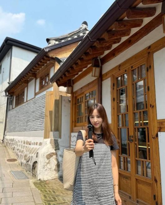 한혜진은 블랙 티셔츠에 깅엄 체크 슬리브리스 원피스를 레이어드하고, 여기에 진청 부츠컷 데님과 블랙 스니커즈를 매치했다. 사진=한혜진 SNS