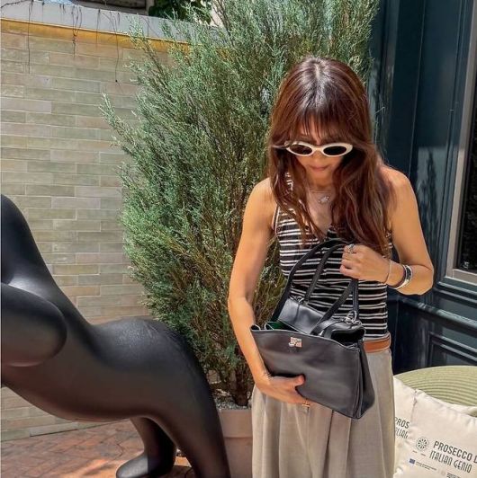 허리에는 브라운 벨트로 실루엣을 정리하고, 화이트 오벌 프레임 선글라스와 실버 주얼리를 레이어드해 시크한 도시 감성을 더했다.사진=채정안 SNS