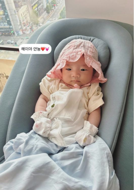 아기 해이는 핑크 보넷을 쓰고 유아용 바운서에 누워 무표정으로 아빠를 응시하고 있다. 사진=손담비 sns