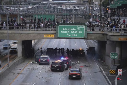 시위대가 전날 밤의 이민 단속 항의 시위에 이어, 2025년 6월 8일 일요일 로스앤젤레스 다운타운의 메트로폴리탄 구치소 근처 101번 고속도로 고가도로 아래에서 대피 중인 캘리포니아 고속도로 순찰대 차량에 물건을 던지고 있다. [사진 = AP 연합뉴스]