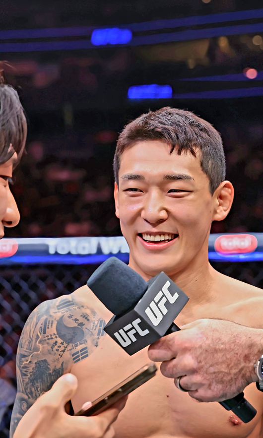대한민국 UFC 23호 파이터로 데뷔한 유주상이 2025년 6월 미국 뉴저지주 뉴어크 프루덴셜 센터 승리 인터뷰에서 통역이 대신 읽는 영어 코멘트를 들으며 웃고 있다. 사진=TKO
