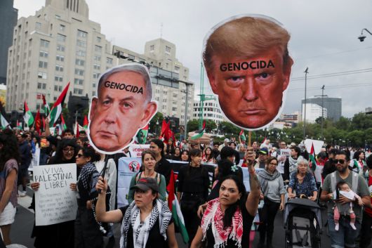 15일(현지시간) 멕시코 멕시코시티에서 시민들이 네타냐후 이스라엘 총리와 트럼프 미국 대통령의 얼굴이 그려진 피켓을 들고 반전 시위를 벌이고 있다. <로이터 연합뉴스>