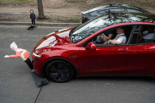 테슬라의 로보 택시 출시를 앞두고 지난 12일 미국 텍사스 오스틴에서 열린 시위에서 한 참가자가 테슬라 모델Y 차량으로 아이 모형 더미를 치고 있다 [사진 출처 = 로이터 연합뉴스]