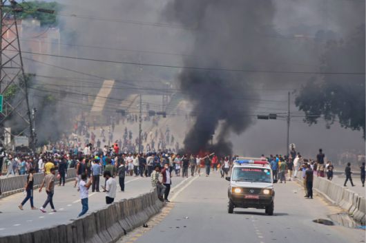 2025년 9월 9일 화요일, 네팔 카트만두에서 구급차가 소셜미디어 금지와 부패에 반대하는 시위대가 거리를 막기 위해 타이어를 불태우는 사이를 지나가고 있다. [AP 연합뉴스]