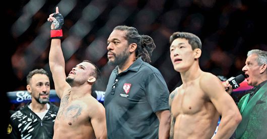 다니에우 구스타부 곤자가 산투스가 2025년 10월 미국 네바다주 패러다이스의 티모바일 아레나 UFC 320 승리 선언을 들으며 감격하고 있다. 오른쪽은 UFC 2연승 무산 및 종합격투기 데뷔 13경기 만에 첫 패배를 당한 후 아쉬워하는 ‘좀비 주니어’ 유주상. 사진=TKO