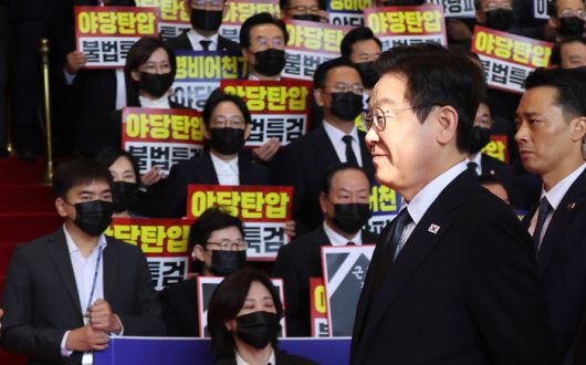 이재명 대통령이 4일 내년도 정부 예산안에 대한 시정연설을 하기 위해 서울 여의도 국회에 도착해 침묵시위를 하는 국민의힘 의원들 앞을 지나고 있다. 국민의힘 의원들은 추경호 전 원내대표에 대한 내란특검팀의 영장청구를 규탄하는 피켓을 들고서 침묵시위를 했다. [국회사진기자단]