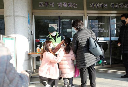 지난 2일 경기도 고양의 한 초등학교에서 학부모와 함께 등교한 학생이 긴급돌봄교실에 들어가기 전 체온 측정을 하고 있다.   연합뉴스
